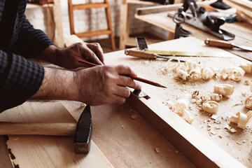 Carpenter makes pencil marks on a wood plank