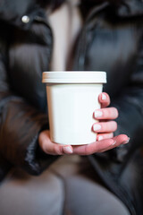 hot drink in a white glass in women's hands