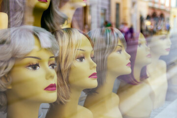Mannequin heads wearing wigs in window of a shop display