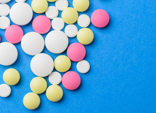 Colored pills on a blue background. The concept of medicine and protection from coronavirus. View from above. Selective focus.