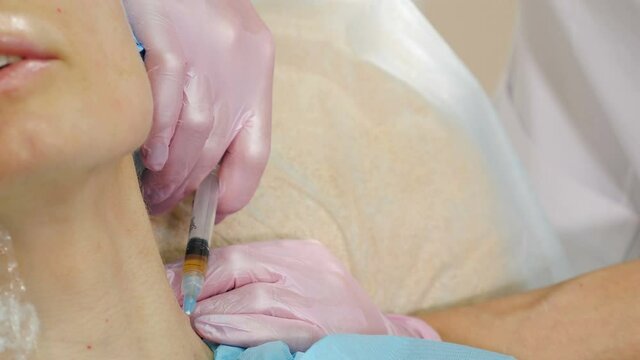 Female patient getting botulinum toxin injections in her neck in beauty salon, Beauty clinic. Beautician hands in gloves making face anti-aging injection in female neck. Beauty facial cosmetology