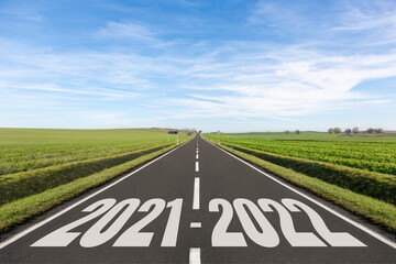 Empty road surrounded by green fields and the years 2021-2022 written	
