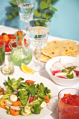 salad of fresh cherry tomatoes, mozzarella, basil and other greens on the dinner table with pita flat bread