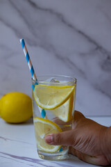 Hand holding a glass of clear lemonade