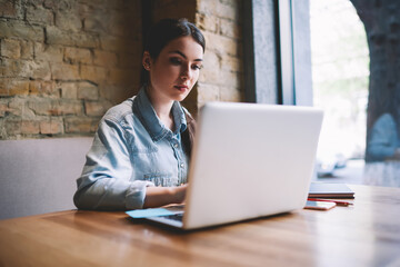 Serious woman typing on laptop during work