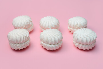 laying out round white marshmallows. pink background