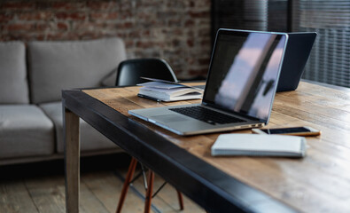 Laptop with screen on the table in the office, phone and notebooks