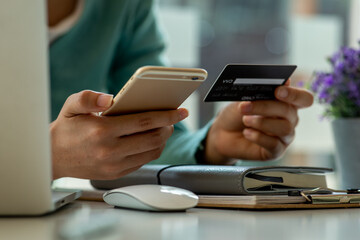 Close up woman hand using credit card and smartphone laptop for buying online shopping