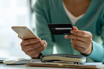 Close up woman hand using credit card and smartphone laptop for buying online shopping