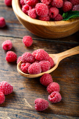 Fresh harvest of raspberries in a wooden spoon