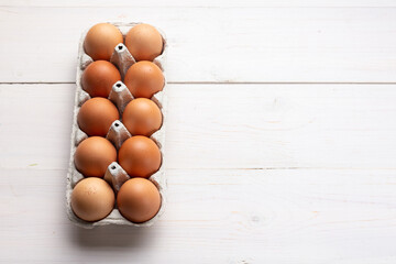 Fresh organic chicken eggs in carton pack or egg container  on white wood background.
