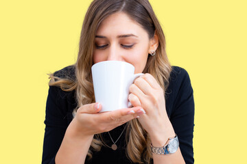 A young girl sitting poses on a yellow background holding a cup.Studio concept