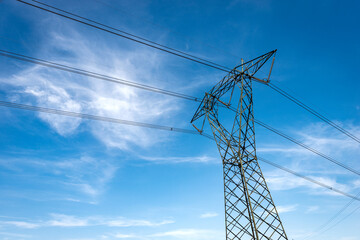 Photography of a High voltage tower, power line with electric cables and insulators against a blue...