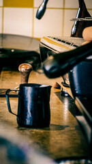 A milk jug ready to have steamed milk poured into it in a cafe.