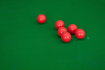 Red snooker balls are on the green table cloth.