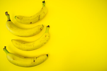Quattro banane su sfondo giallo posizionate sul lato sinistro