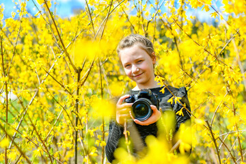 A young girl photographs nature in the park with a SLR camera.