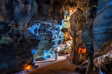 Beautiful girl in white dress walking in blue cave, Thailand.