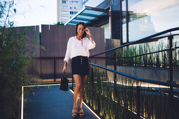 Obraz premium Carefree Caucasian female tourist in optical spectacles for provide eyes correction walking and smiling, happy woman 30 years old dressed in trendy clothing outfit enjoying leisure time in city