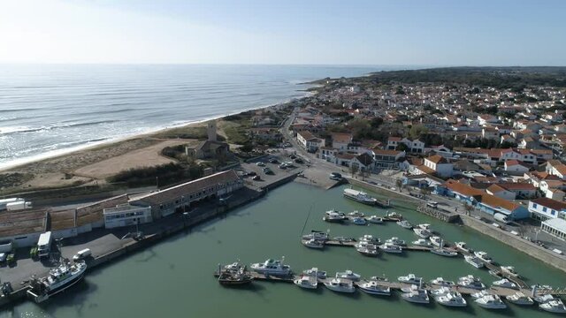 Marina boats, lighthouse and church at the fishing village of La Cotiniere in Oleron Island France, Aerial dolly out shot