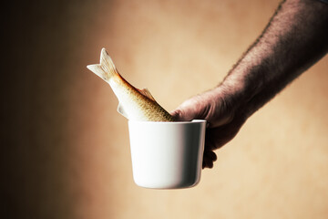 hand holding cup with fish
