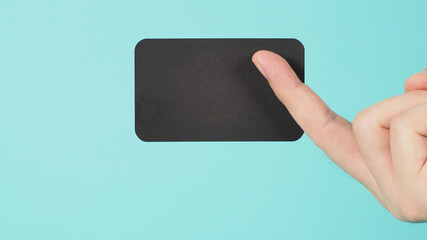 Empty space for text.Male hand holding black blank card isolated on mint green or Tiffany Blue...