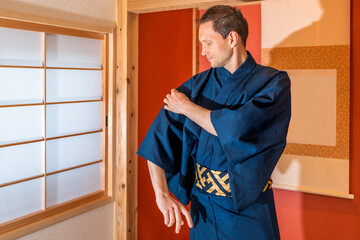 Traditional japanese machiya house room with window and red alcove with hanging scroll and man in...