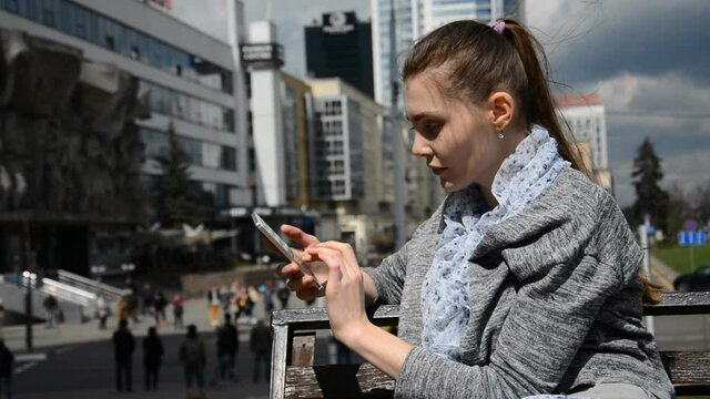 Cheerful caucasian female student using smartphone