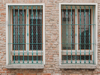 Brick wall with two identical windows, both with grating.