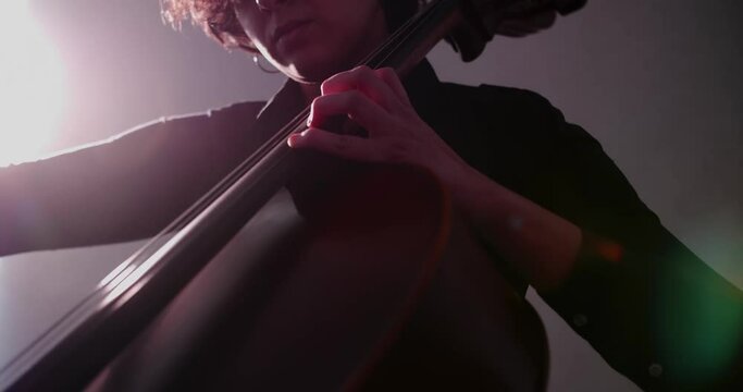 Young woman playing cello rehearsing for a concert