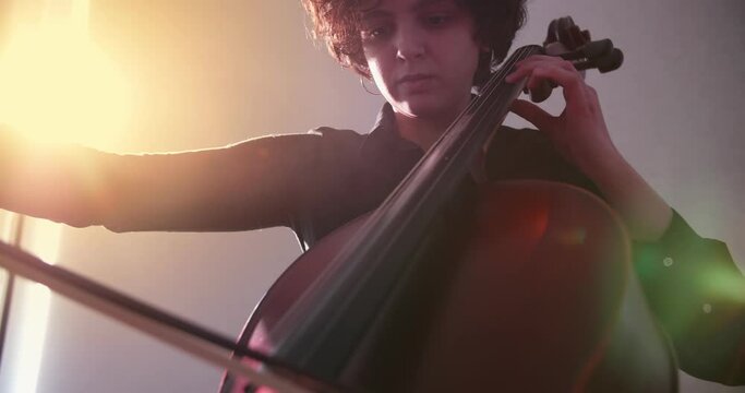 Female Cellist Playing Cello rehearsing at home