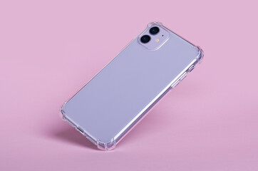 Purple smartphone iphone 11 in clear silicone case falls down, back view isolated on pink...
