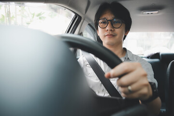 Obraz premium Handsome young asian man using safety belt while driving a car