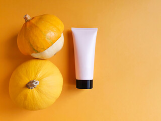 Mockup of light pink squeeze tube with black cap for branding and yellow pumpkins on yellow...