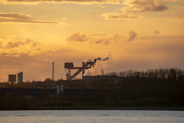 Smoking chimneys of an industrial plant at sunset. Ecological concept.