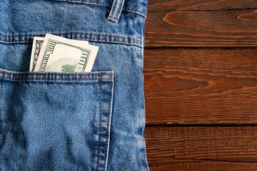 Money in pocket. Dollar bill in jeans pocket on a wooden background. Copy space. Concept of making and saving money.