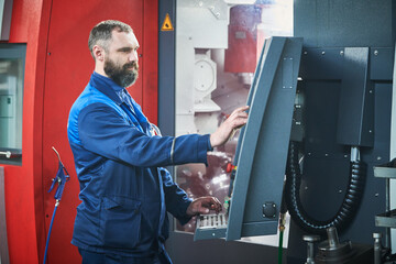 Industrial worker operating cnc machine at metal machining industry