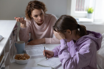 Nervous mother explaining educational material to stressed unhappy young adolescent kid, scolding...