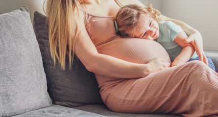 Little baby girl relaxing on mom's pregnant belly - Pregnant mother with a toddler - Family concept