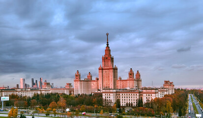 Fototapeta premium Aerial panoramic view of sunset campus buildings of famous Moscow university under dramatic cloudy sky in autumn
