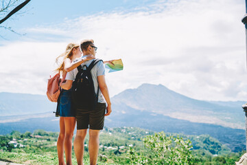 Unrecognizable couple of tourists standing on hill and enjoying landscape