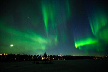 A multi colour Northern Lights on the night sky over a city. Aurora Borealis over Swedish lake Islands. Northern Sweden