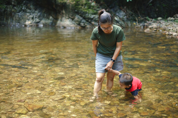 Asian mother playing with her son at waterfall