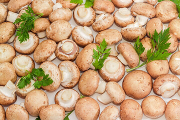 Background of raw brown button mushrooms with parsley, top view