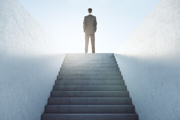 Business success concept with businessman on top of stairs looking at blue sky.
