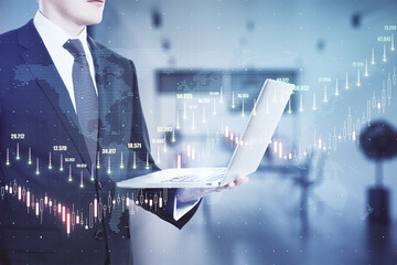 Businessman with a laptop in an office room with a raising chart in the background. Trading and market analysis concept