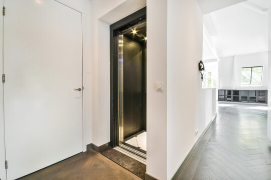 Interior of spacious hallway with metal elevator and tiled floor in contemporary residential building