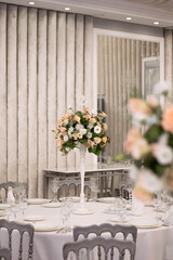 Centerpiece made of green leaves and fresh flowers stands on the dinner table. Wedding day. Fresh flowers decorations.
