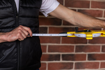Man's hands holding length centimetre ruler for building use against red brick wall. Copy space....