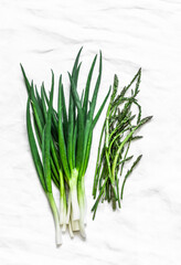 Green onions and young asparagus on a light background, top view